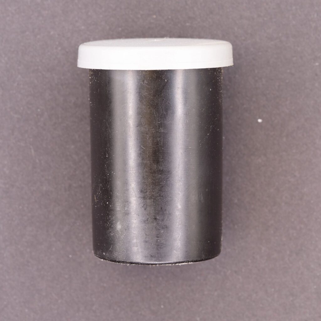 Black 35mm film canister with white cap